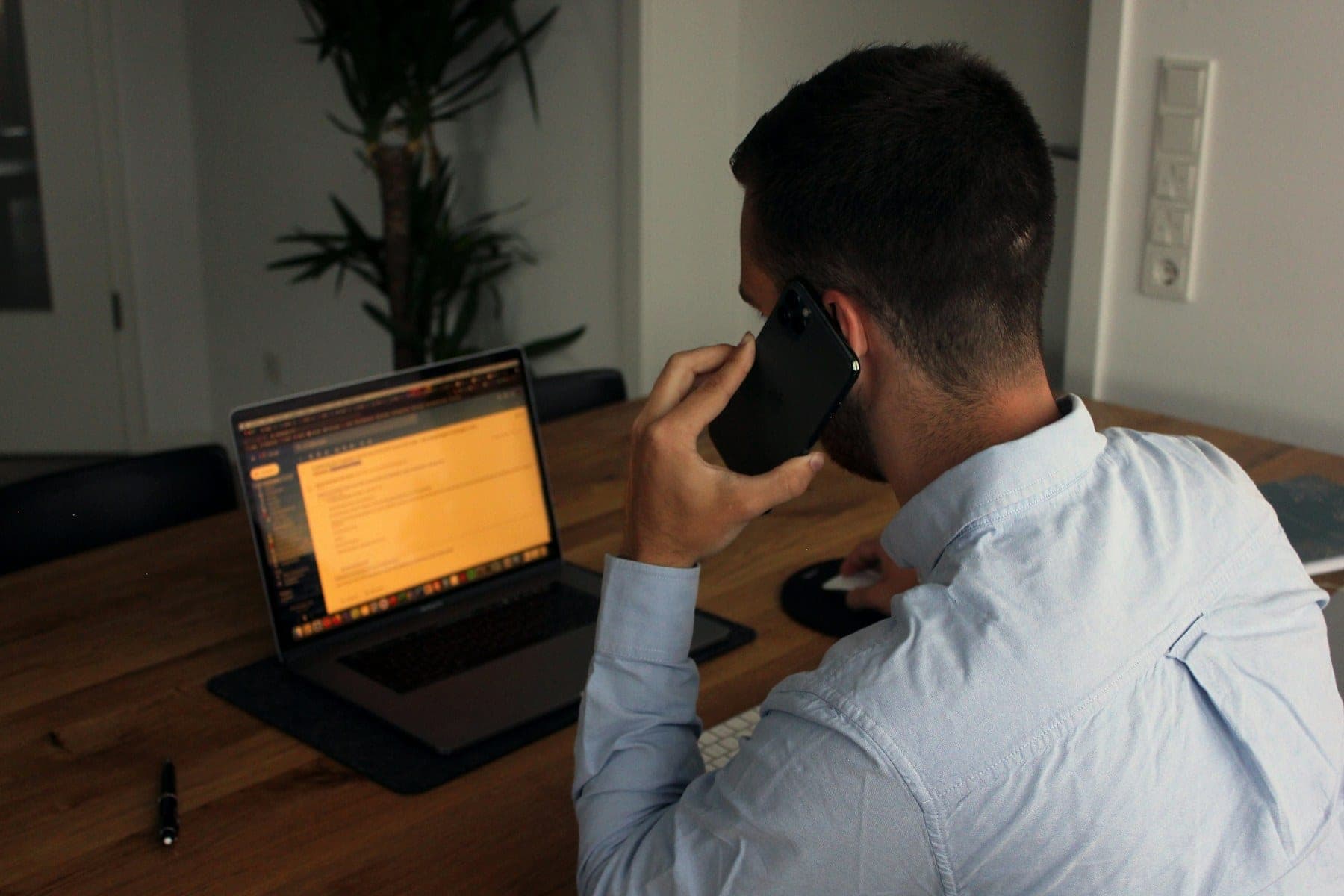 Logistics coordinator seen from behind talking on the phone while working on a laptop