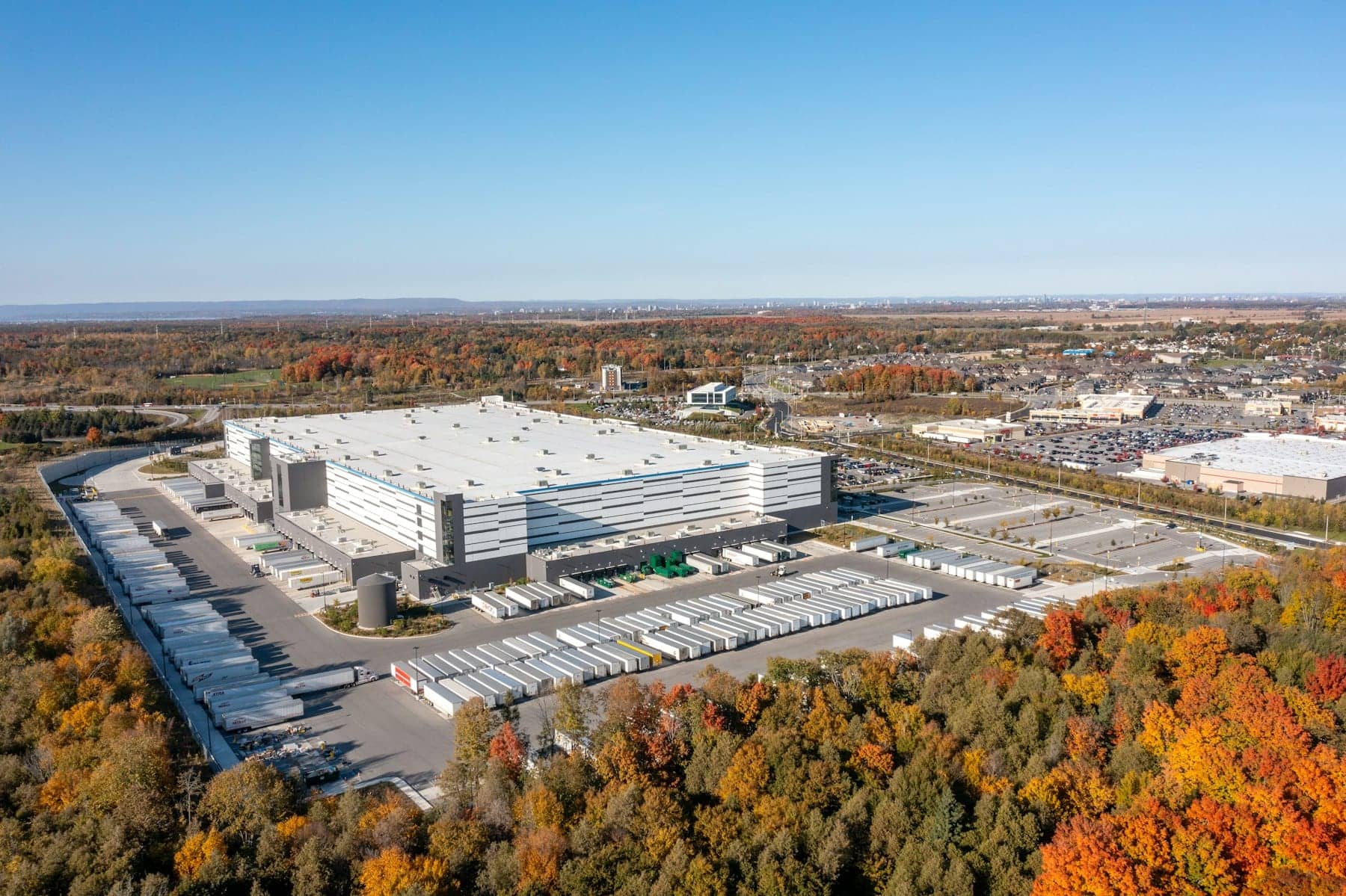 Aerial view of a large distribution center with rows of semi trailers at its loading docks and in the yard