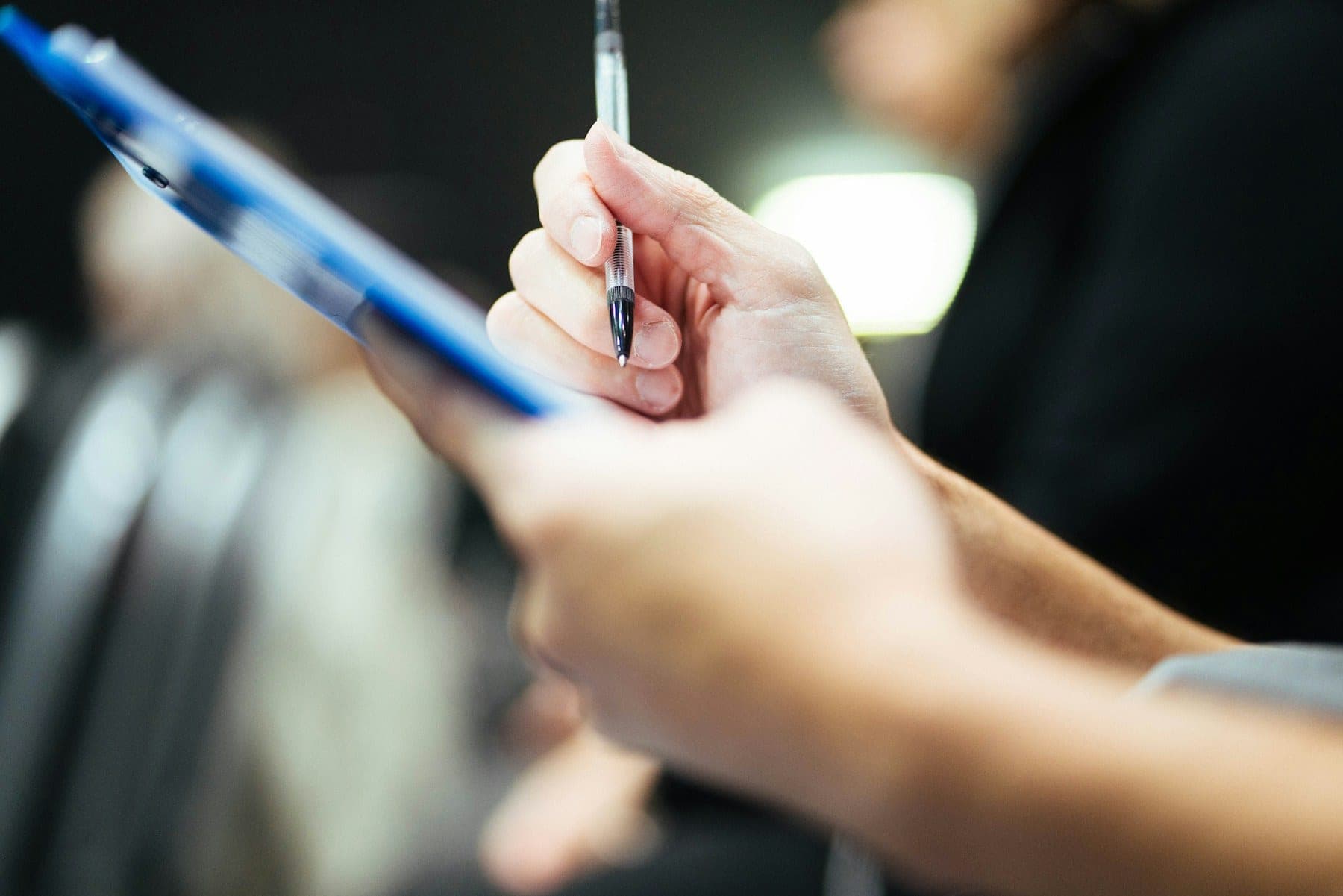 Close-up of a hand holding a pen over a clipboard of shipping paperwork